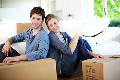 couple sitting on the floor surrounding by boxes smiling at camera